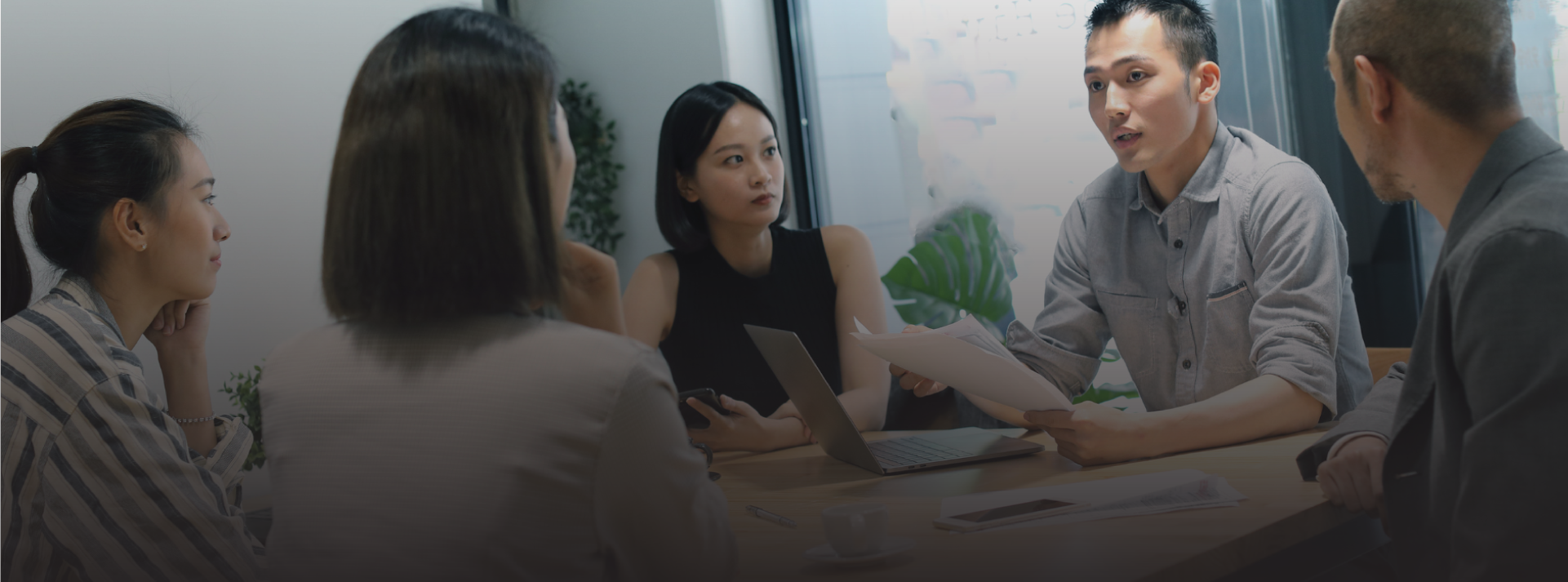 Five colleagues in discussion around a table in a meeting room